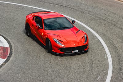 Ferrari with carbon-fibre front splitter and side skirts taking a tight corner on track, showcasing aerodynamic performance