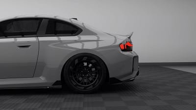 Side rear quarter view of BMW G87 M2 showcasing carbon fibre rear spoiler, diffuser, and custom forged wheels in stealth finish